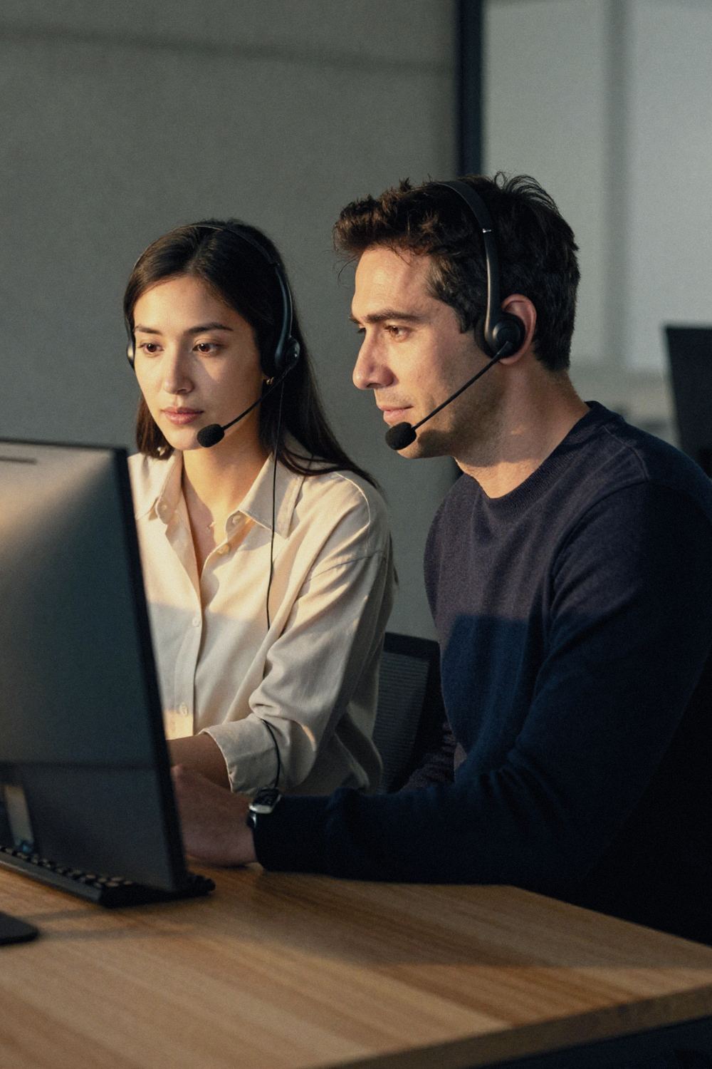 Two representatives review a call flow on a monitor